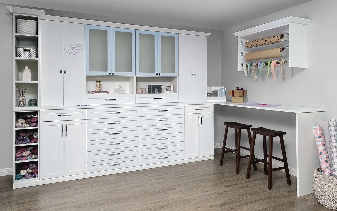 Custom antique white craft room cabinets and built-in work desks in Broward County by Closets Beyond