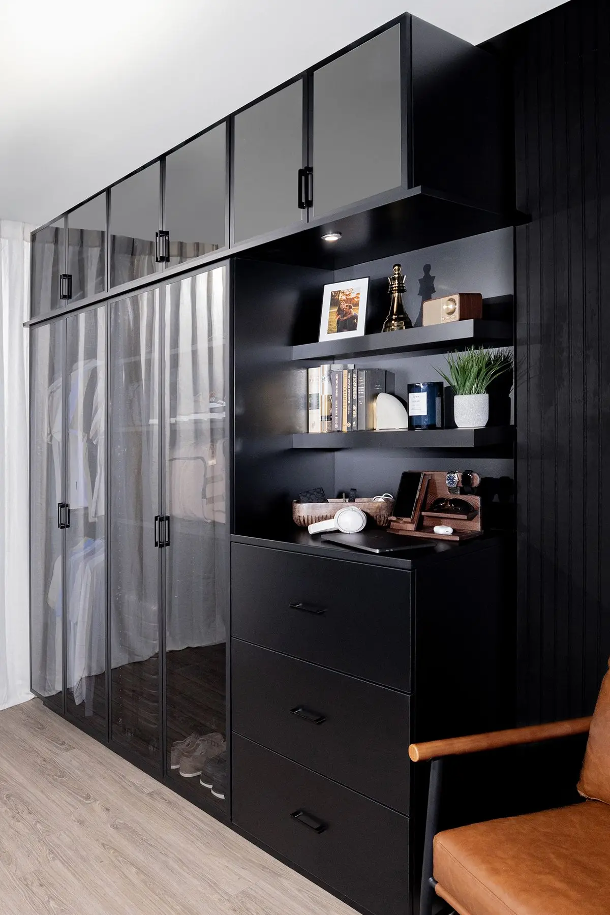 Minimalist black wardrobe closet featuring tinted glass doors and internal lighting