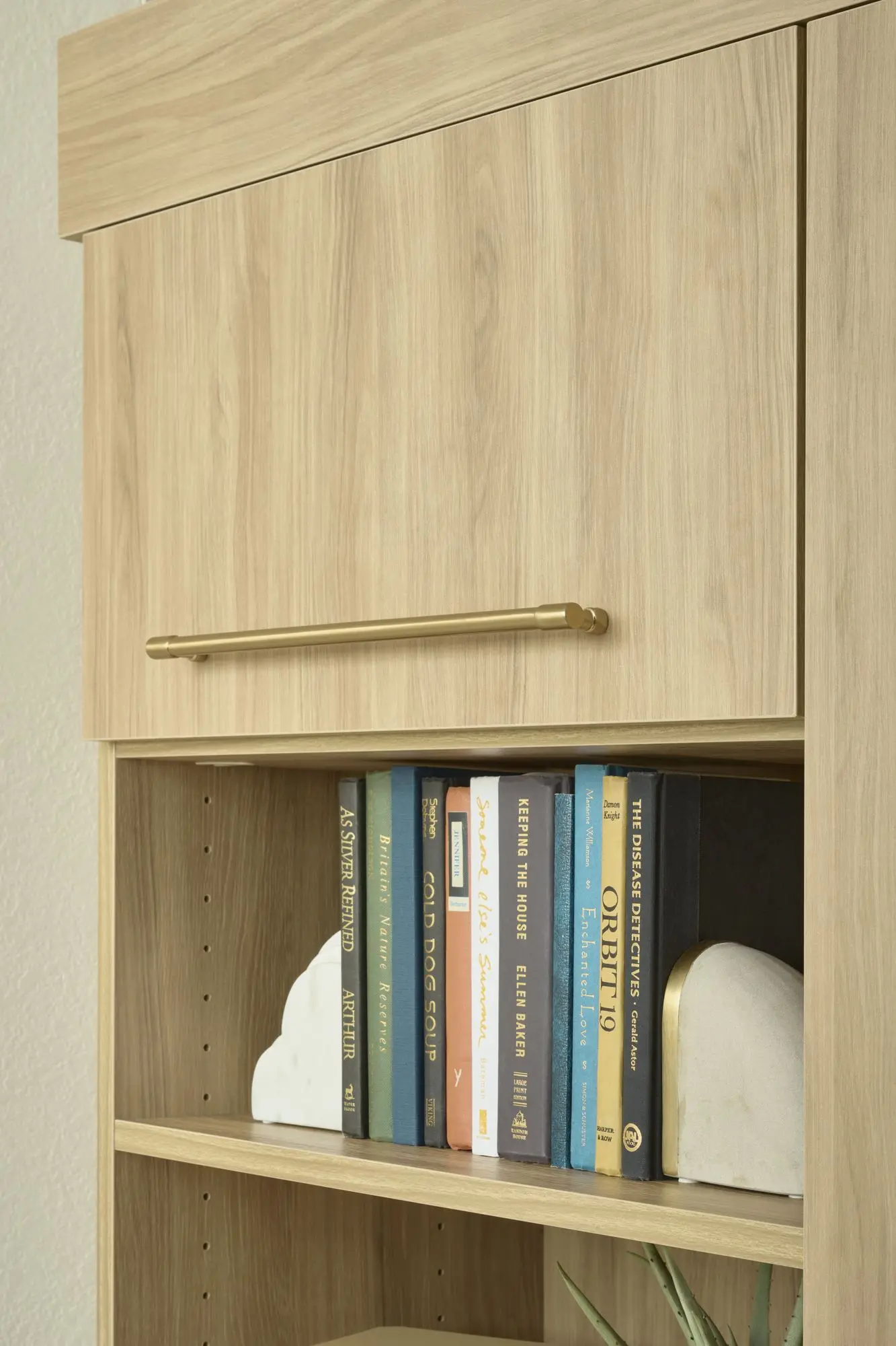 Custom oak bookshelf system with elegant gold bar hardware pulls and integrated storage cabinets