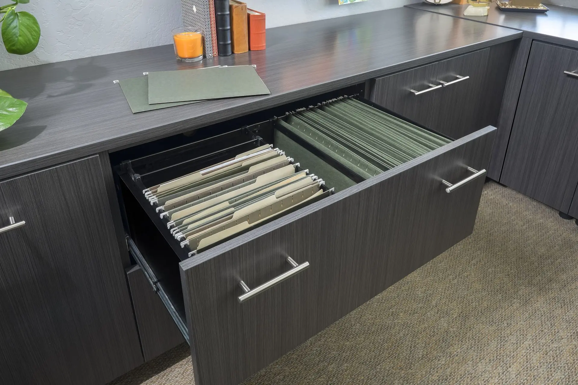 Open drawer of a dark licorice woodgrain custom office desk filled with green hanging file folders