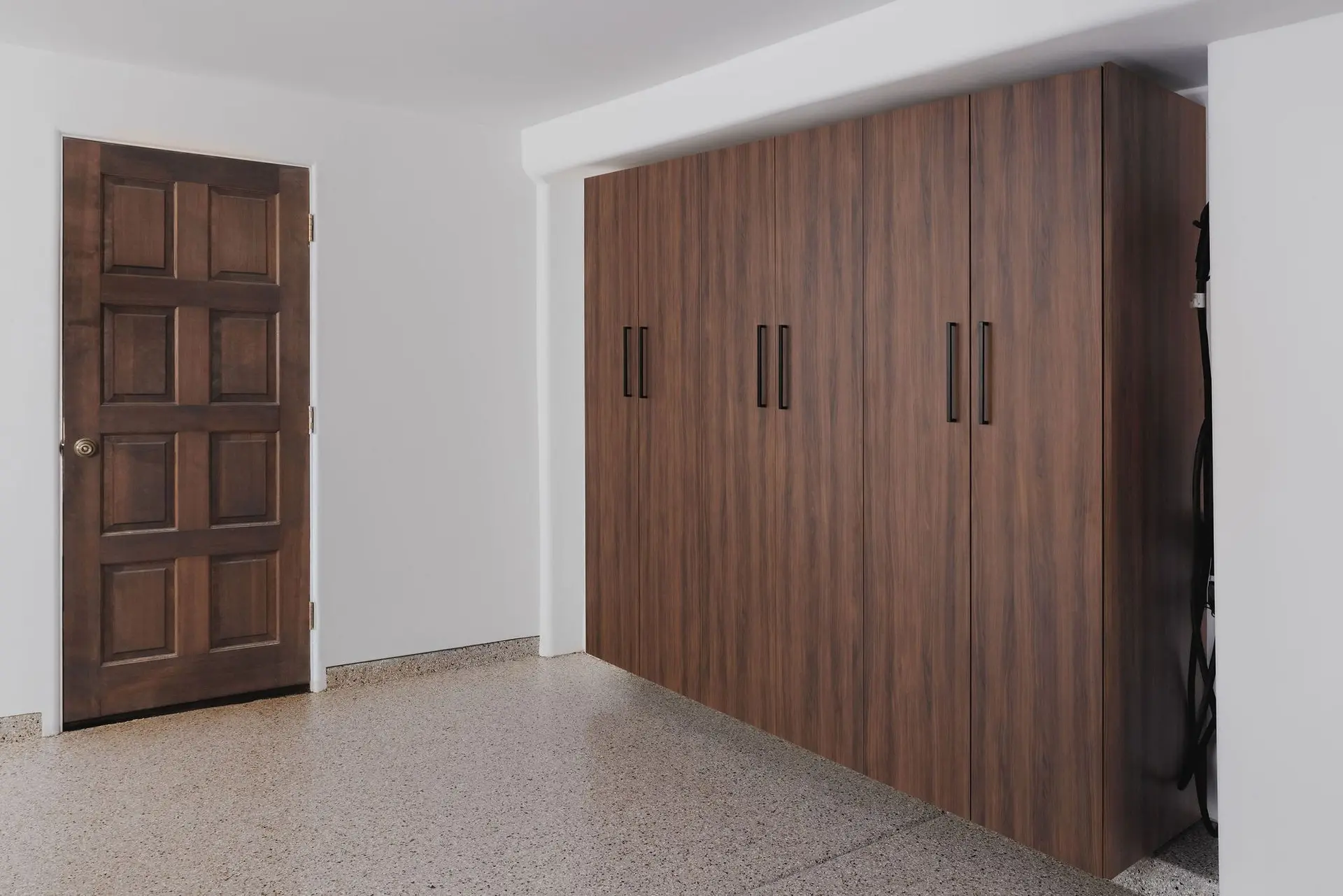 Streamlined wood finish custom garage cabinets spanning a home storage area
