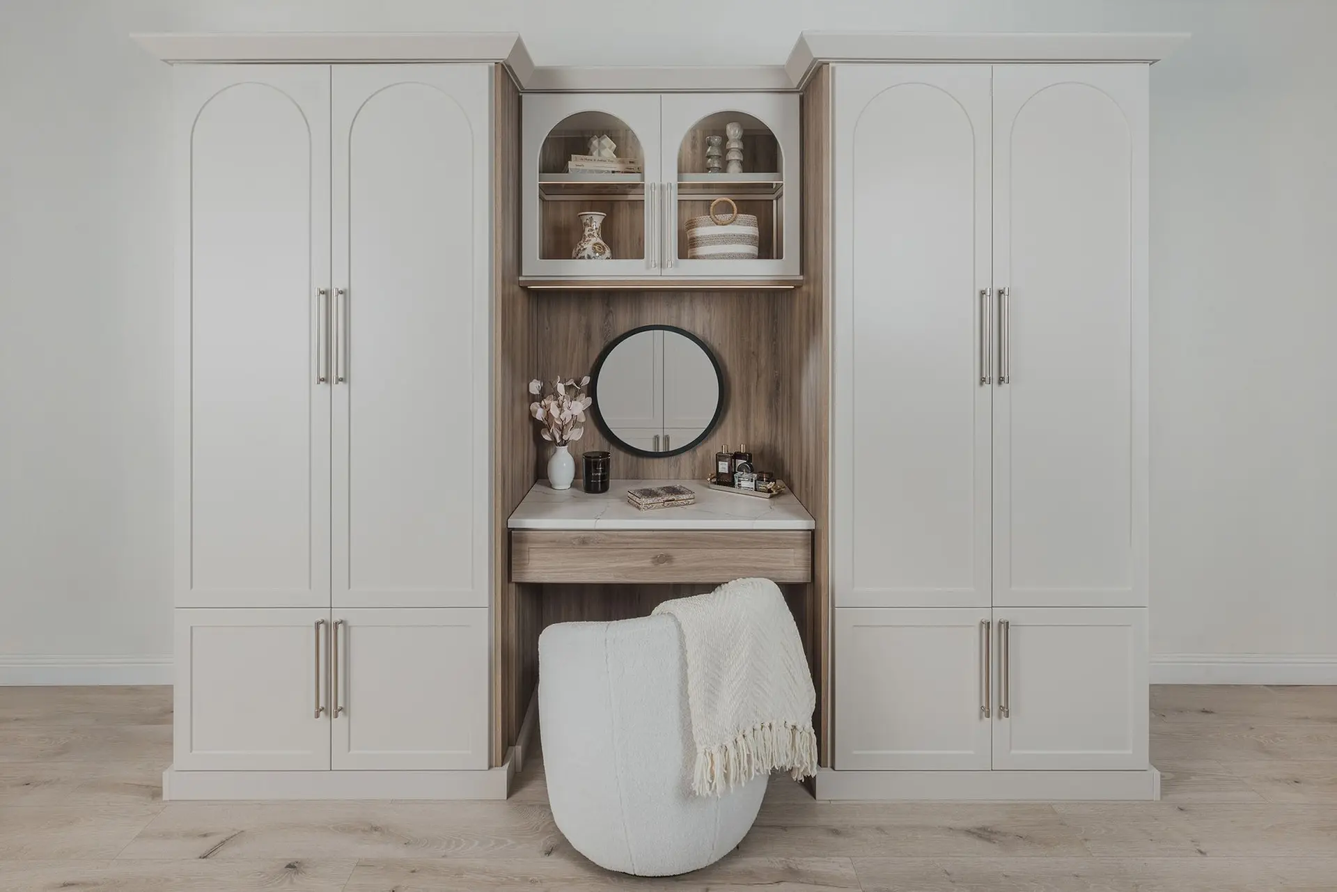 Light wood custom wardrobe system featuring open compartments and a vanity mirror