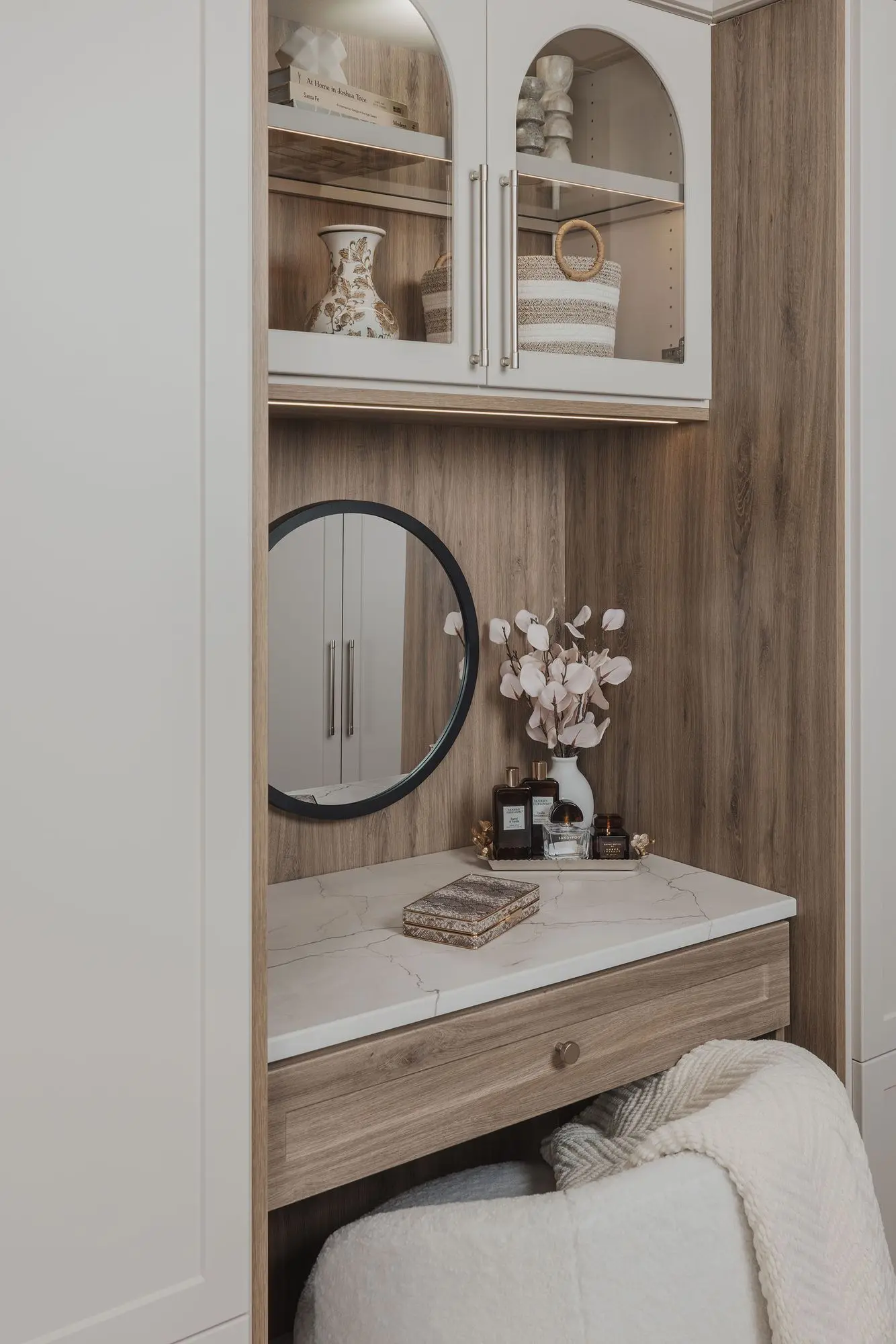 Close up of a round black framed mirror on a light wood vanity unit