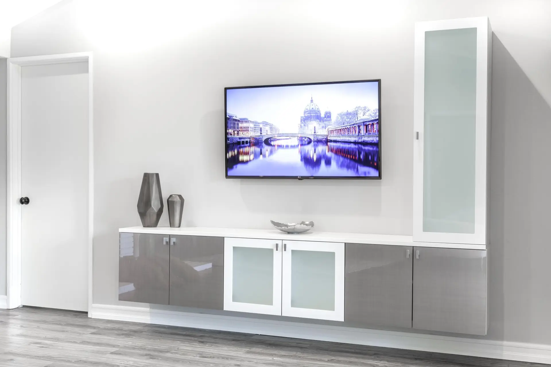 Custom white entertainment center with modern shaker cabinets and flat screen TV mounting