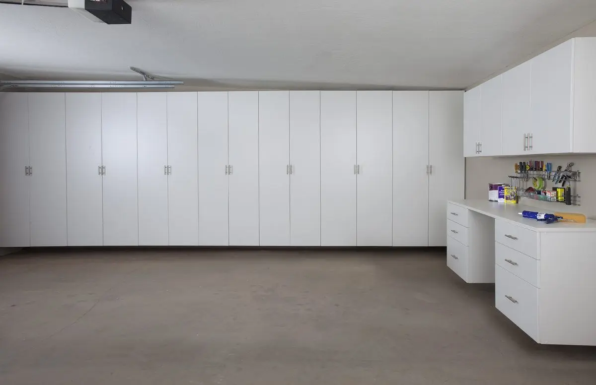 Custom white garage cabinets installed along a wall for seamless storage