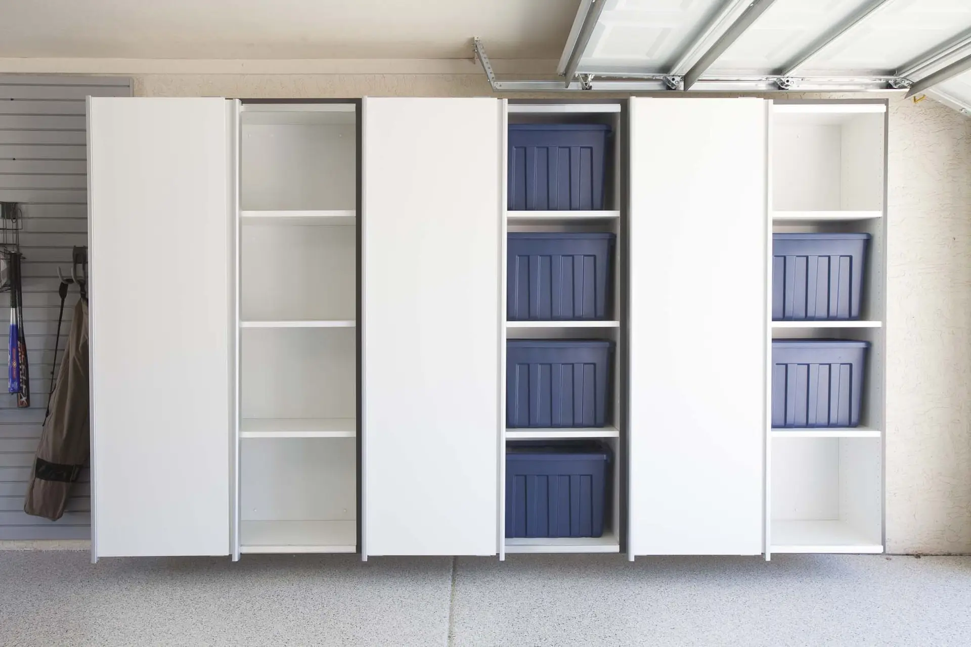Custom white garage closets featuring integrated blue pull-out storage bins in Deerfield Beach