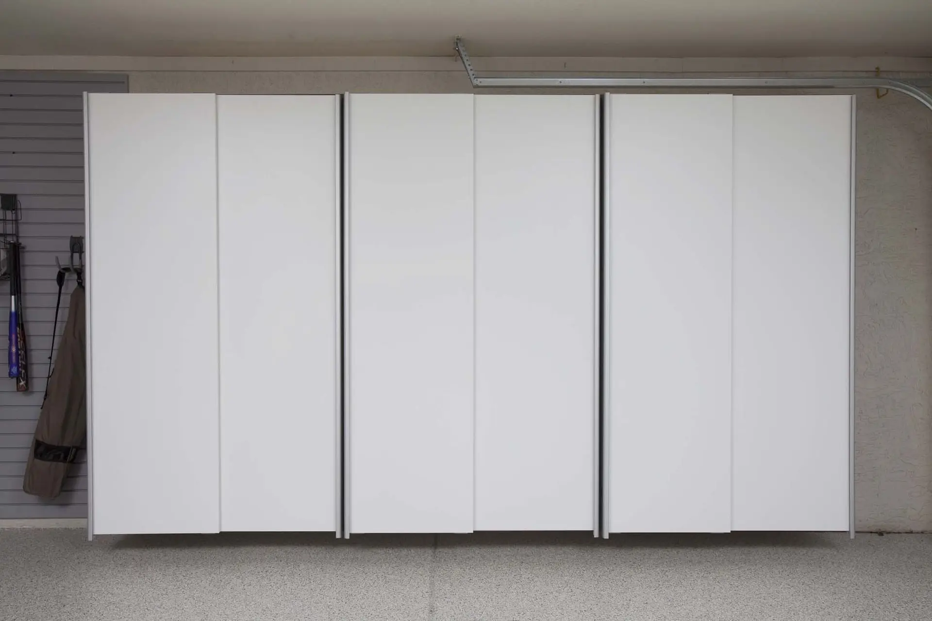 Modern white garage cabinet system spanning a full residential wall
