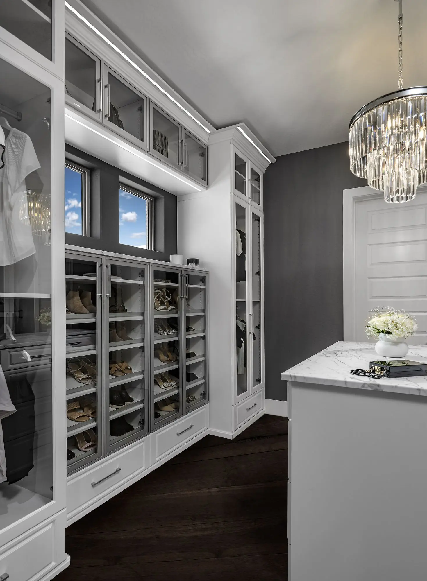 Luxury white walk-in closet design featuring a custom center island and elegant chandelier